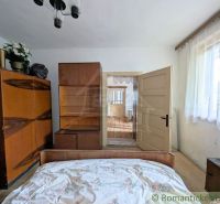 Interior of a family house with wooden cabinets and a bed, light walls, curtains.