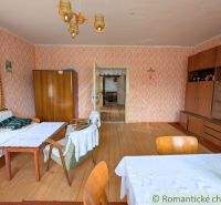 A room in a family house with a wooden decor floor, classic furniture, and patterned wallpaper.