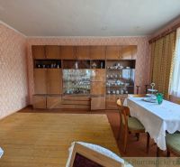 Living room in a family house with furniture, wooden decor flooring, and a dining table.