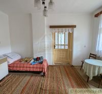 Interior of a family house with a bed, table, and carpet.