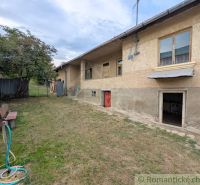 A family house in Nižné Ladičkovce, simple exterior, garden with lawn and bench.