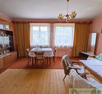 Living room with retro furniture, wood-patterned flooring, and floral curtains in a family house.