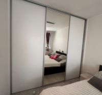 A bedroom in a 3-room apartment with a built-in wardrobe and a floor with a wooden decor.