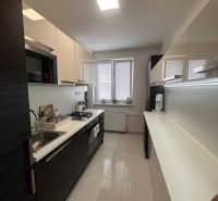 A kitchen in a 3-room apartment with built-in appliances and white tiles.