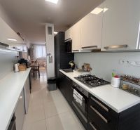 A kitchen in a 3-room apartment with glossy cabinets and white tiles.