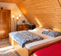 A cozy bedroom in a cabin with wooden paneling and a decorative carpet.