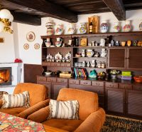 A fireplace in a cottage with rustic furniture, decorative vases, and comfortable armchairs.