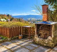 Sunny terrace with a stone fireplace in the Cottage in Banská Štiavnica, overlooking the surrounding landscape.