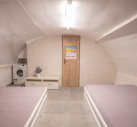 Attic room in a family house with beds, a cabinet, and a washing machine.