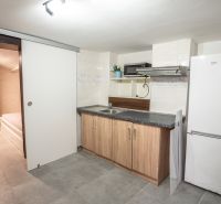 A kitchen in a family house with a refrigerator, sink, and light ceramic tiles.