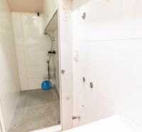 Shower corner with white tiles in the bathroom of a family house.