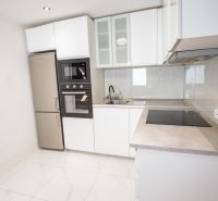 A kitchen in a family house with white cabinets, built-in appliances, and tiles.