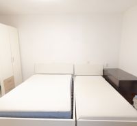 A bedroom in a family house with two beds, a large wardrobe, and simple furniture.