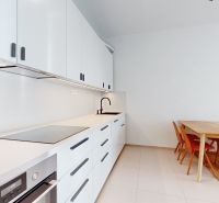 A kitchen in a 4-room apartment with white cabinets and a dining table.
