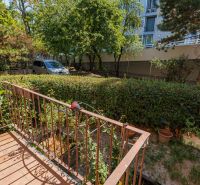 A garden with a 4-room apartment with a terrace and a view of greenery, a fence, and trees.
