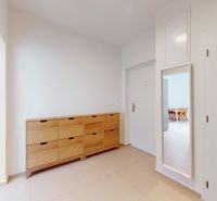 In the hallway section of the 4-room apartment, there is a wooden shoe cabinet and a mirror.
