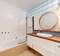 A bathroom with a bathtub, sink, and mirror, in a 4-room apartment.