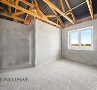 The interior of a family house with wooden beams and a large window, walls with plaster.