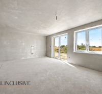A spacious room in a family house with large windows and an unfinished floor.