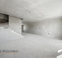 A spacious interior of an unfinished family house with a concrete staircase and bare walls.