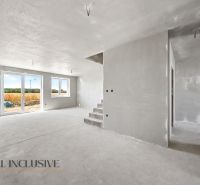 A view into the interior of a family house with a concrete floor and stairs.