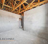 Interior of a family house with raw walls and exposed wooden beams on the ceiling.