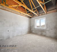 An unfinished room in a family house with a view of the roof beams and a window.