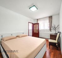A bright bedroom with a comfortable bed and a wooden decor floor in a family house.