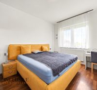 Bedroom in a family house with a wooden decor floor, contains a bed and a work desk.