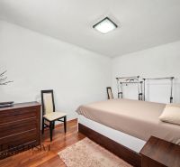 Bedroom with a bed, drawer chest, and wooden decor flooring in a family house.