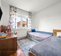 Children's room with two beds, a television, and a wooden decor floor in a family house.