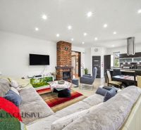 Living room of a family house with a brick fireplace, sofa, and dining area.