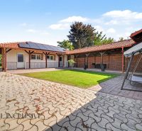 A family house in Kostolné Kračany with a yard, lawn, swing bench, and solar panels.