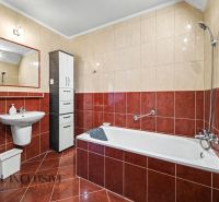 A bathroom in a family house with a bathtub, a sink, and a cabinet, tiled.