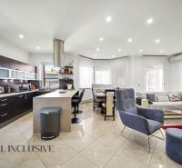 Living room in a family house with a kitchen, dining area, and a light-colored sofa.