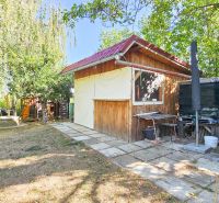 A cottage in Suchá nad Parnou surrounded by greenery, with a small terrace and a bench.