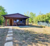 A cottage in Suchá nad Parnou with a wooden terrace and a garden surrounded by greenery.