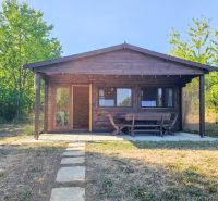 A wooden cottage in Suchá nad Parnou with an outdoor seating area and a garden, surrounded by greenery.