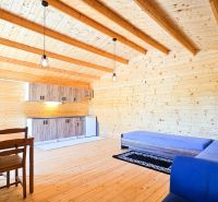 The interior of a cabin with a wood-patterned floor, a blue sofa, and a wooden table.