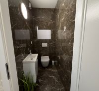 Bathroom in a 2-room apartment with a mirror, sink, and marble tiles.