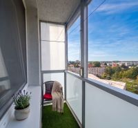Balcony of a 3-room apartment in Šaľa with a view of the city, a flower pot, and a chair.