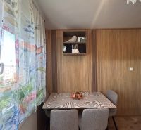 A dining room with wooden decor, a patterned table, and floral curtains in a 3-room apartment.