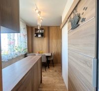 A kitchen in a 3-room apartment with a wooden decor floor and a dining table.