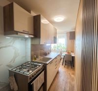 A kitchen in a 3-room apartment with a wooden decor floor and a dining area.