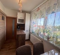 Bright kitchen in a 3-room apartment with a wooden decor floor and colorful curtains.
