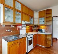 A kitchen with built-in cabinets and appliances in a 4-room apartment with a wooden decor floor.