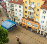 A building with commercial spaces on Moyzesova Street in Púchov, lined with trees.