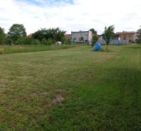 A garden with a lawn surrounded by houses in Beladice, designated for residential plots.