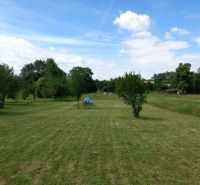 A plot for residential use in Beladice with maintained grass and scattered trees.