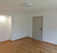 A bright room with wood-decor flooring and white walls in a two-room apartment.